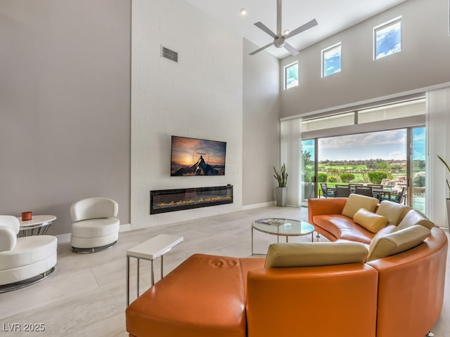 living room with ceiling fan, a towering ceiling, light tile patterned flooring, and a wealth of natural light