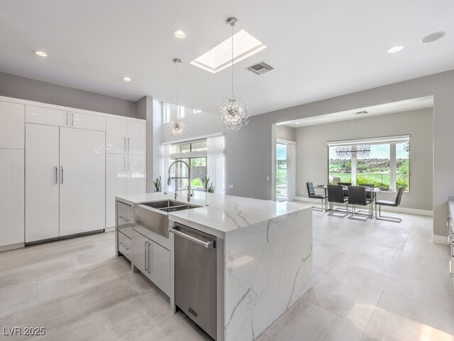 kitchen featuring a center island with sink, light stone countertops, pendant lighting, stainless steel dishwasher, and white cabinets