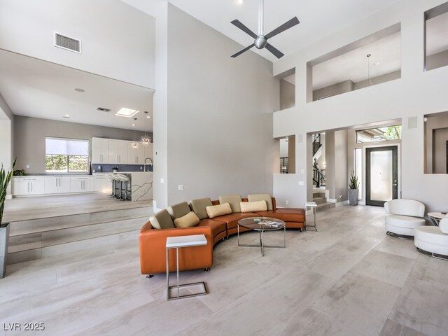 living room featuring ceiling fan and a towering ceiling