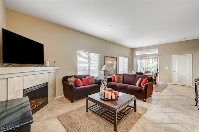 tiled living room with a notable chandelier, a tile fireplace, and plenty of natural light