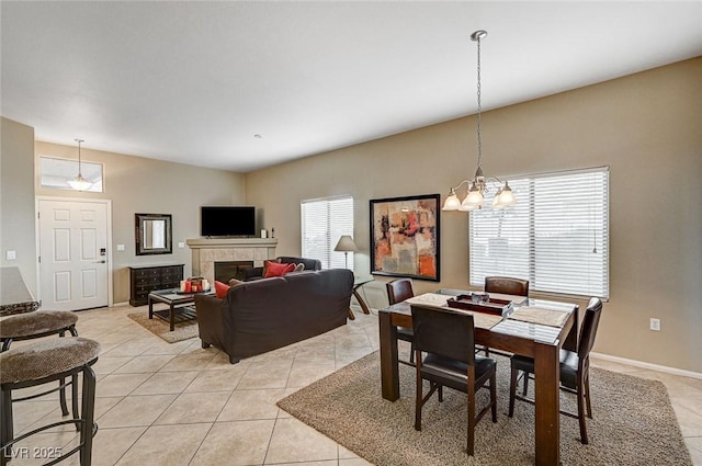 tiled dining room featuring a tile fireplace and an inviting chandelier