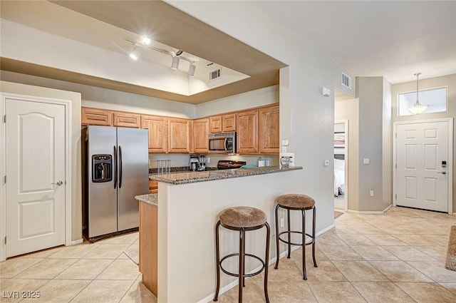 kitchen with a kitchen breakfast bar, kitchen peninsula, stone countertops, pendant lighting, and appliances with stainless steel finishes