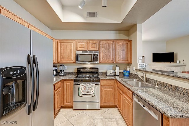 kitchen featuring stainless steel appliances, sink, light tile patterned floors, and a tray ceiling