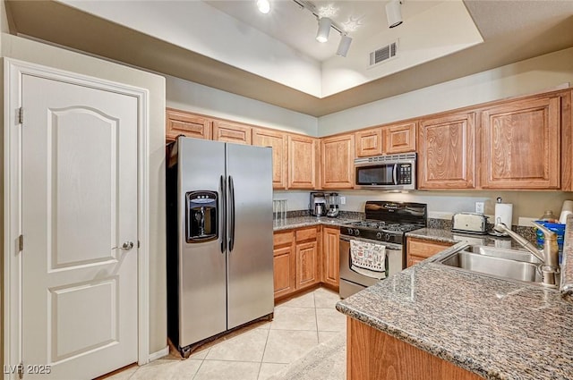 kitchen with stainless steel appliances, track lighting, a tray ceiling, light tile patterned flooring, and sink