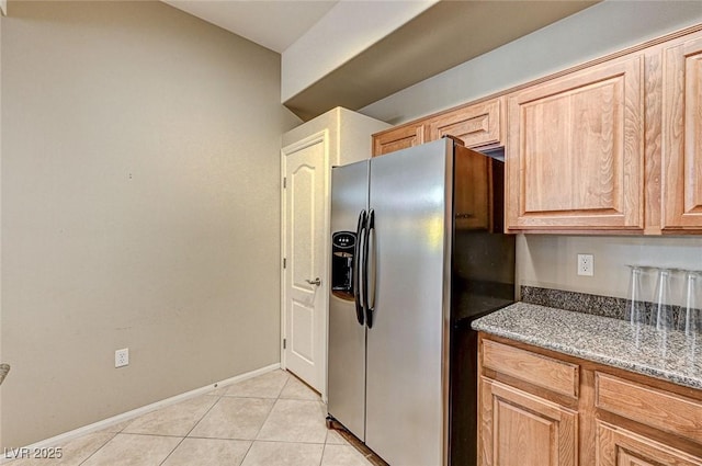 kitchen featuring stainless steel fridge with ice dispenser, light brown cabinetry, light tile patterned flooring, and light stone countertops