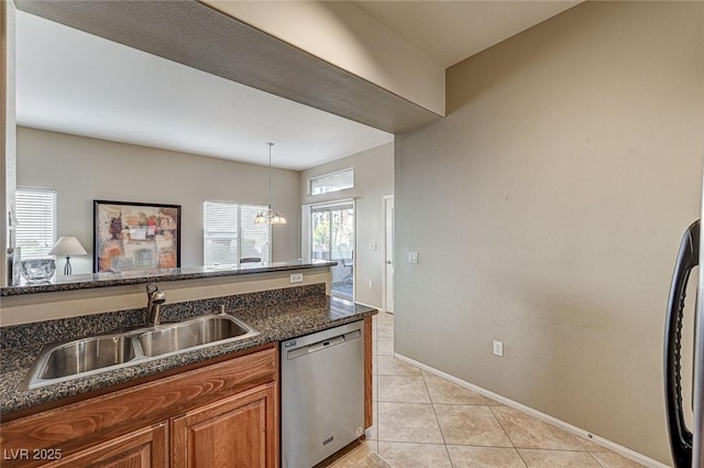 kitchen featuring sink, dishwasher, dark stone countertops, light tile patterned floors, and hanging light fixtures