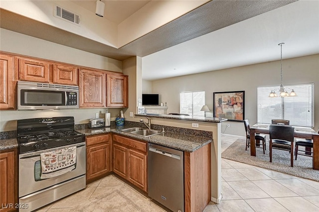 kitchen featuring appliances with stainless steel finishes, kitchen peninsula, a notable chandelier, pendant lighting, and sink