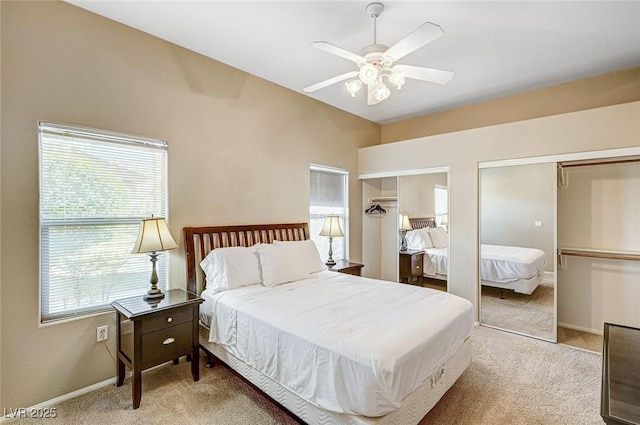 bedroom with two closets, ceiling fan, and light carpet