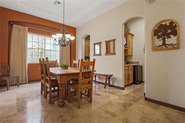 dining area featuring a raised ceiling and a chandelier