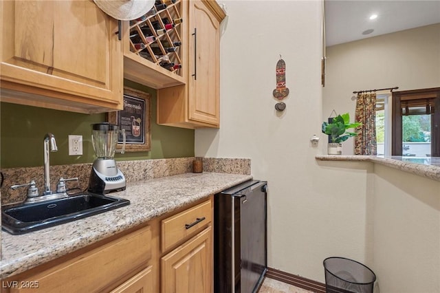 kitchen featuring sink, beverage cooler, light stone countertops, and light brown cabinets