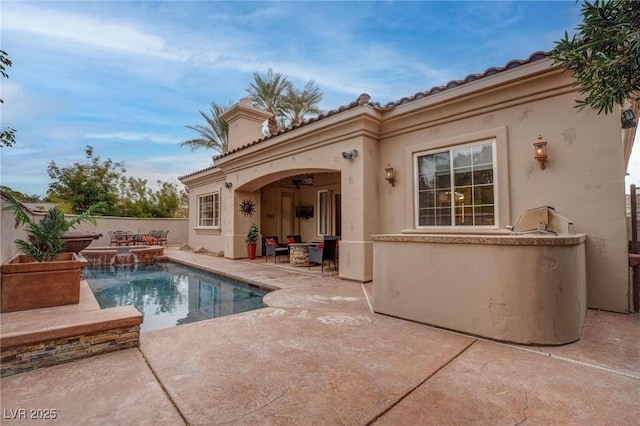 rear view of house with pool water feature, a fenced in pool, and a patio area