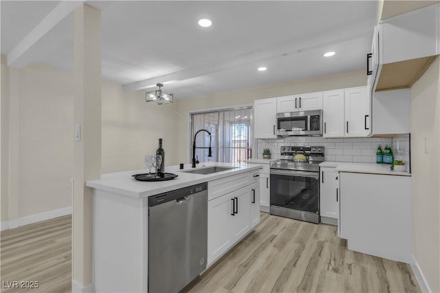 kitchen with stainless steel appliances, white cabinets, sink, and light hardwood / wood-style flooring