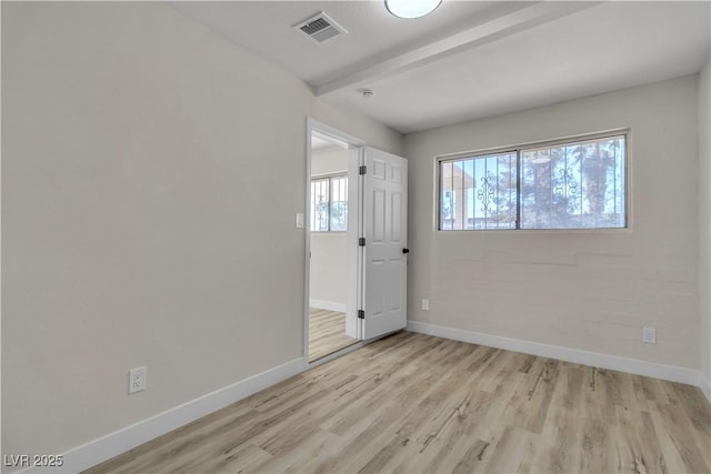 spare room featuring light hardwood / wood-style floors and beamed ceiling