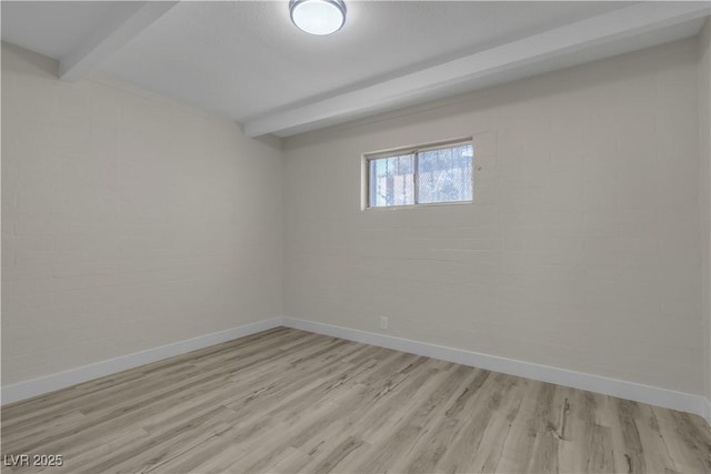 empty room featuring light hardwood / wood-style floors and beamed ceiling