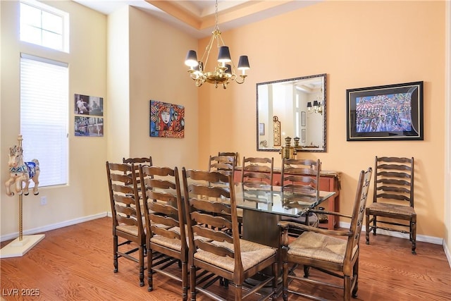 dining room featuring a notable chandelier, a towering ceiling, and wood-type flooring