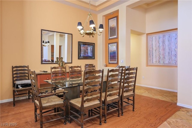 dining space with a towering ceiling, an inviting chandelier, and light hardwood / wood-style flooring