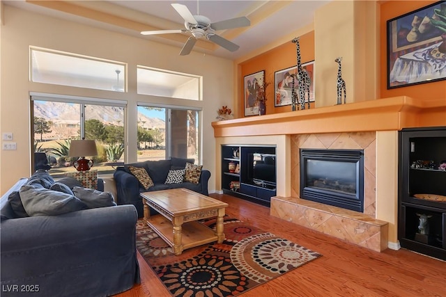 living room with a high end fireplace, hardwood / wood-style floors, and ceiling fan