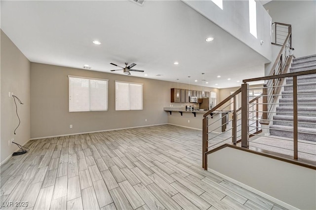 unfurnished living room featuring ceiling fan and light wood-type flooring