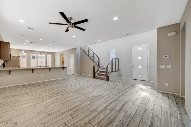 unfurnished living room featuring ceiling fan and sink