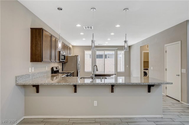 kitchen with decorative light fixtures, kitchen peninsula, appliances with stainless steel finishes, and a kitchen breakfast bar