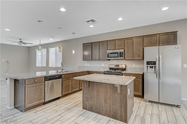 kitchen featuring ceiling fan, a center island, pendant lighting, sink, and appliances with stainless steel finishes