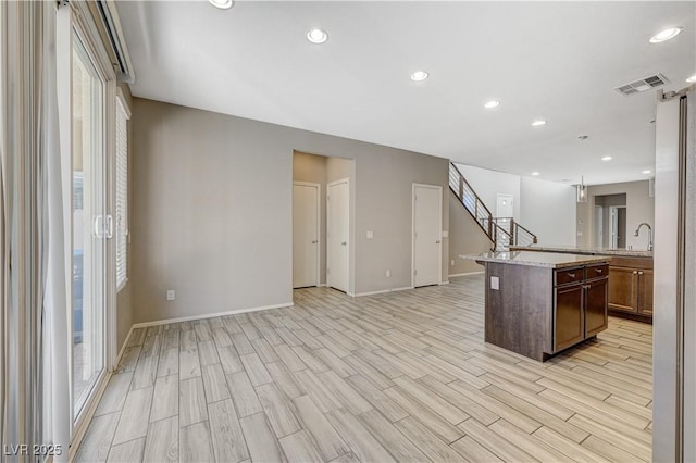 kitchen featuring decorative light fixtures, sink, light hardwood / wood-style floors, and a kitchen island with sink