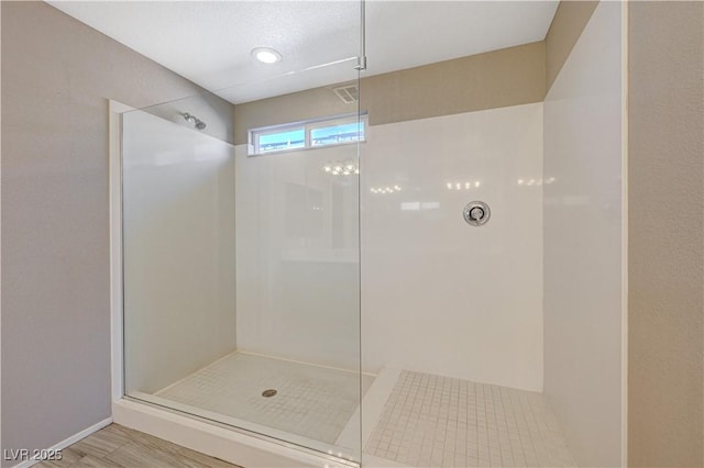 bathroom with a textured ceiling, tiled shower, and hardwood / wood-style flooring