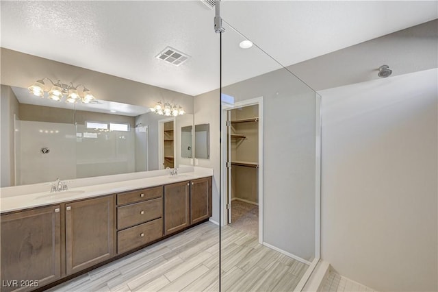 bathroom featuring walk in shower, vanity, and a textured ceiling