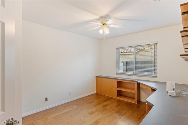 unfurnished room with hardwood / wood-style flooring, built in desk, and ceiling fan