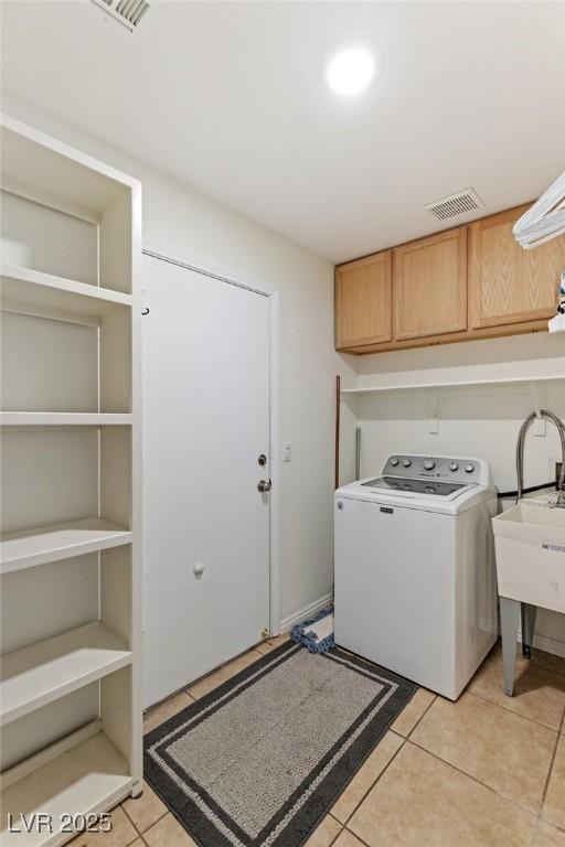 laundry area featuring sink, washer / clothes dryer, light tile patterned floors, and cabinets