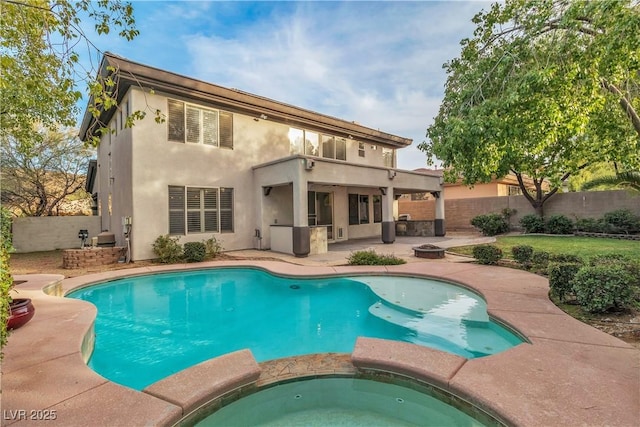 rear view of property featuring an outdoor kitchen, a patio area, and a swimming pool with hot tub