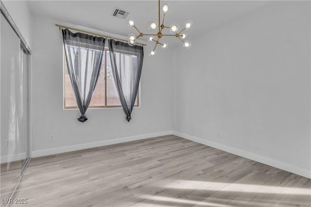 unfurnished room with light wood-type flooring and a chandelier