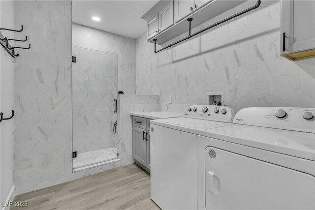 laundry area with cabinets, light wood-type flooring, and washing machine and clothes dryer