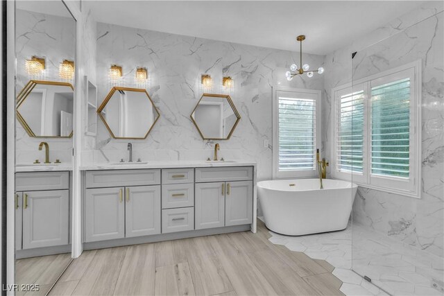 bathroom featuring a bath, vanity, a chandelier, and wood-type flooring