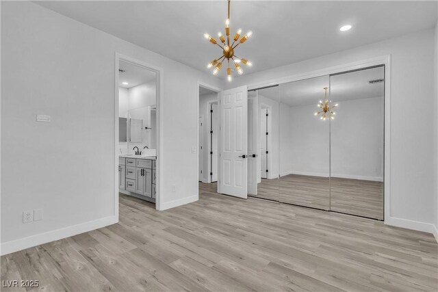 interior space featuring sink, an inviting chandelier, light hardwood / wood-style floors, a closet, and ensuite bath