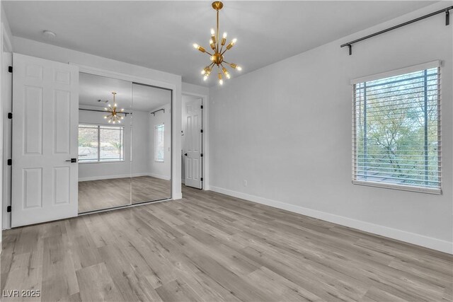 unfurnished bedroom featuring light wood-type flooring, a closet, and a chandelier