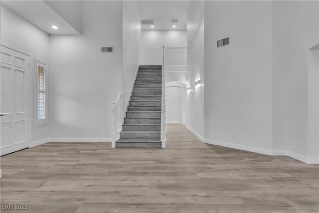 stairs with a high ceiling and wood-type flooring