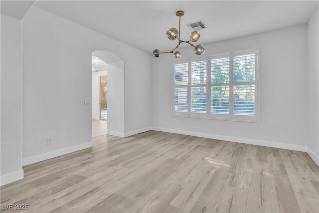 spare room featuring light hardwood / wood-style floors and an inviting chandelier