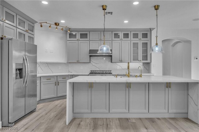 kitchen with stainless steel appliances, gray cabinets, pendant lighting, and an island with sink