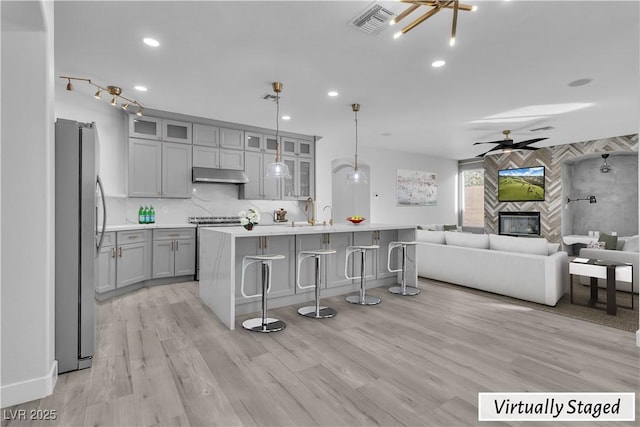 kitchen featuring stainless steel refrigerator, gray cabinetry, hanging light fixtures, a fireplace, and decorative backsplash