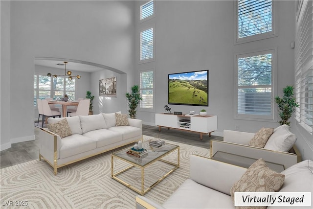 living room with a towering ceiling, hardwood / wood-style floors, and a chandelier