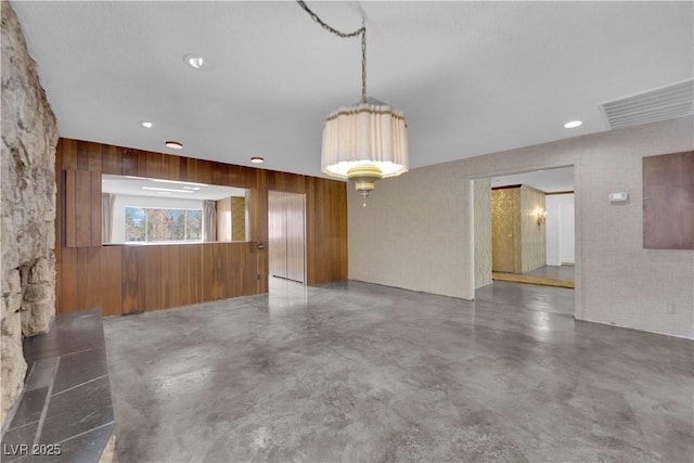 spare room featuring concrete floors and wood walls