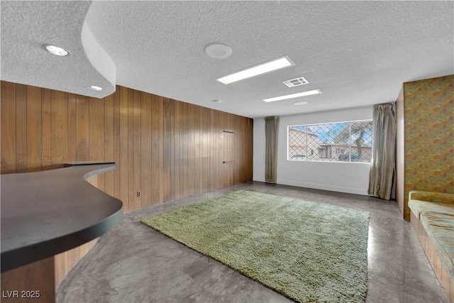 interior space featuring wooden walls, concrete flooring, and a textured ceiling