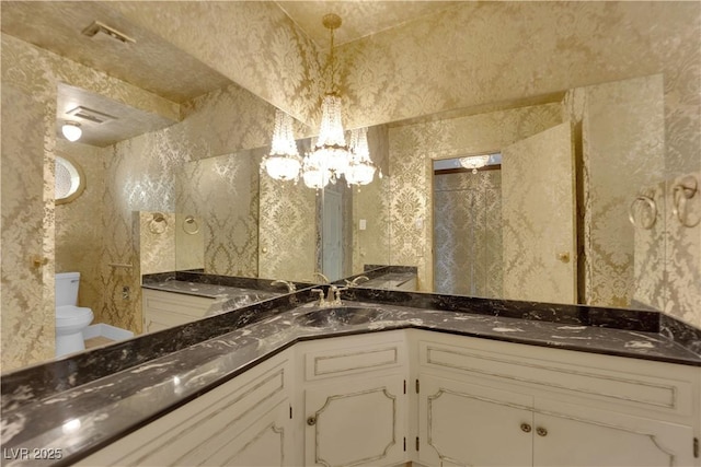 bathroom with vanity, toilet, and a chandelier