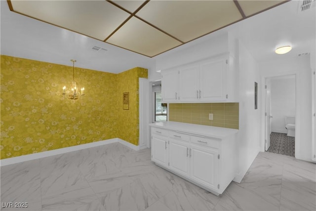 kitchen featuring decorative light fixtures, white cabinets, a notable chandelier, and decorative backsplash