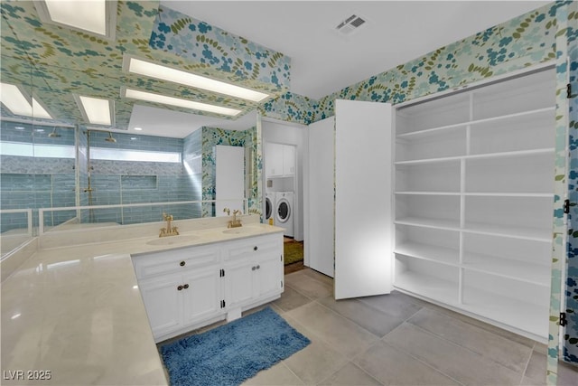 bathroom with tile patterned flooring, washing machine and dryer, and vanity