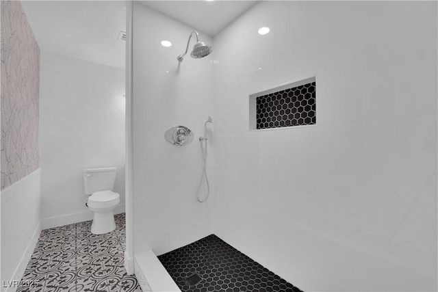 bathroom featuring tiled shower, toilet, and tile patterned flooring