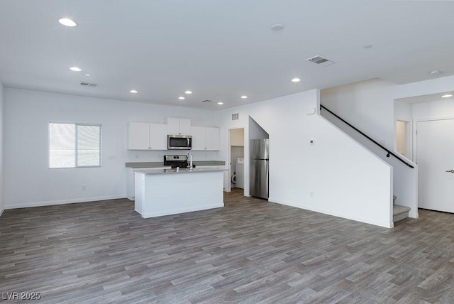 kitchen featuring light hardwood / wood-style flooring, stainless steel appliances, white cabinetry, and a center island with sink