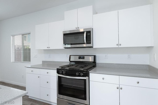 kitchen featuring appliances with stainless steel finishes, white cabinets, and wood-type flooring