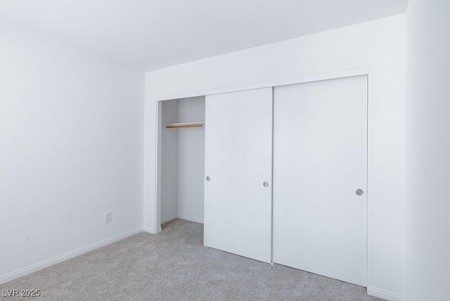 unfurnished bedroom featuring a closet and light colored carpet